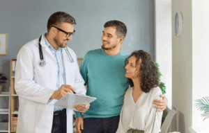 Lekarz omawia z parą korzyści wynikające z wykonania badań genetycznych przed planowaniem ciąży