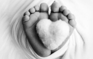 Stópki niemowlęcia ułożone z miękkim sercem, symbolizujące pamięć i troskę po utracie ciąży.
